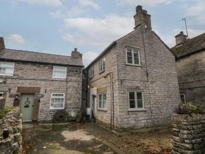 an old stone house in the middle of two buildings at The Cottage on the Island in Castleton