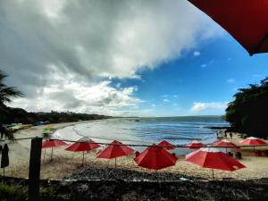 a group of red umbrellas on a beach at Pousada Odoyá Beach - Quádrupla in Conde