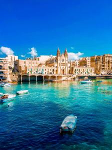 a boat in the water in front of a city at LA88 Cityway Apartment 5 in Il-Gżira