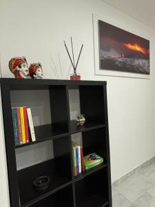 una libreria nera con libri e statuette sopra di Terranera a Catania