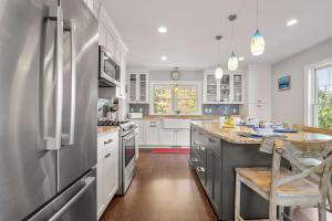 a kitchen with white cabinets and a stainless steel refrigerator at Oasis near beach Pool large yard and airy kitchen in Orleans