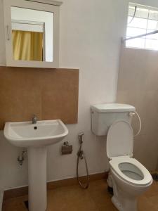 une salle de bain avec des toilettes blanches et un lavabo dans l'établissement Karanda Cottage at Kotte, à Sri Jayewardenepura Kotte
