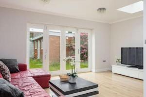 a living room with a red couch and a tv at Tudor house · Kingston luxury 5 bed villa in Whitton