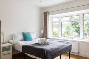 a bedroom with a bed with blue pillows and a window at Tudor house · Kingston luxury 5 bed villa in Whitton