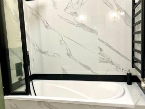 a white tub in a bathroom with a glass shower at Schreyer Apartman in Nagykanizsa +26 photos
