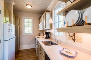 a kitchen with a sink and a white refrigerator at Belize Carriage House in Rosemary Beach +17 photos