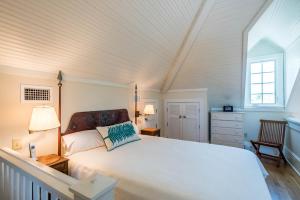 a bedroom with a large white bed and a window at Belize Carriage House in Rosemary Beach