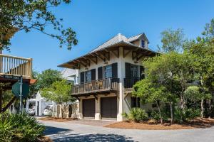 a large house with a balcony on a street at Belize Carriage House in Rosemary Beach