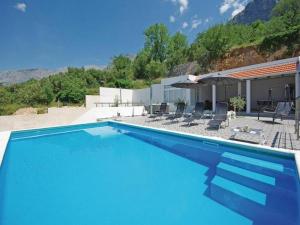 a blue swimming pool with chairs and umbrellas at Relaxing Villa with swimming pool, jacuzzi and entertainment equipment in Podgora