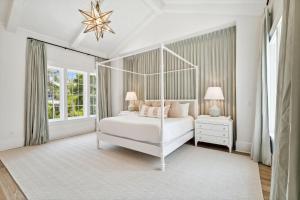 a white bedroom with a canopy bed and two lamps at Beach Bear Cottage in Watersound Beach +40 photos