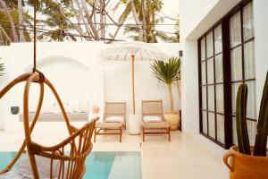 a patio with chairs and a swimming pool at Inlander Villas A- Private pool luxury Villa in Gili Trawangan
