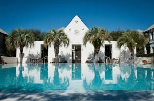 a building with palm trees in front of a swimming pool at Brighton Cottage in Rosemary Beach