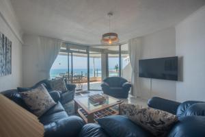 a living room with a blue couch and a television at La Crete Sands no 3 in Uvongo Beach
