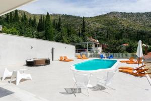 a patio with a pool and chairs and a grill at Exclusive Villa with Sea View in Zaton