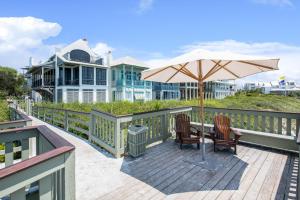 a table with an umbrella and two chairs on a deck at Oasis Cottage & Carriage House in Rosemary Beach