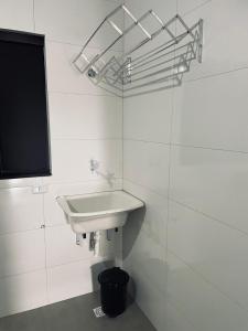 a white bathroom with a sink and a trash can at Pousada frente Hecad e leilomaster in Goiânia