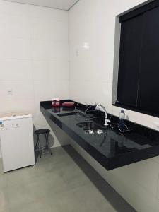 a black counter with a large television on a wall at Pousada frente Hecad e leilomaster in Goiânia +4 photos