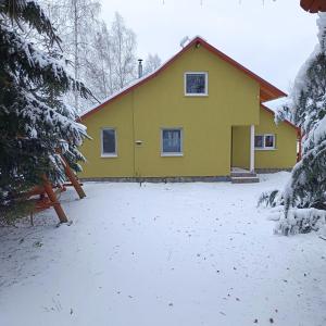 a yellow house with snow in front of it at Csergő Kulcsosház in Senetea