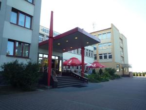 a building with red umbrellas in front of a building at Carina Hotel in Tczew
