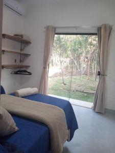 a bedroom with a bed and a large window at Casa Beija-flor no Vale do Capão in Palmeiras