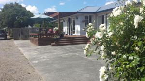 a house with a bench and an umbrella at Scottbase B and B in Feilding