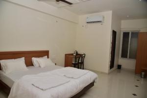 a bedroom with a large bed with white sheets at NV Comforts in Rānībennur