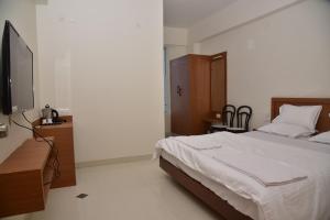 a bedroom with a bed and a flat screen tv at NV Comforts in Rānībennur