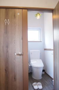 a bathroom with a toilet and a wooden door at ゲストハウスはれのち in Furunoushigawa +40 photos