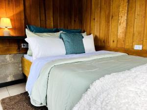 a bedroom with a large bed with white sheets and blue pillows at Cabaña La Finca in Cervantes