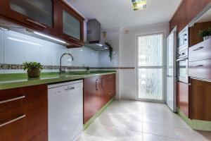 a kitchen with wooden cabinets and a white dishwasher at Amplio y Luminoso 3 Rooms Parking in Jerez de la Frontera