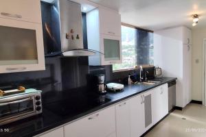a kitchen with white cabinets and a black counter top at Condominio en Zona Privilegiada, Tranquila y Segura in Caracas