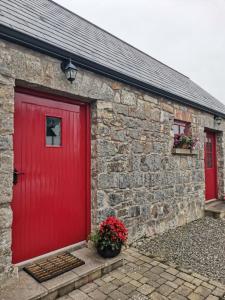 a brick building with a red door and two windows at Minnie’s Cottage in Killylea