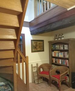 a room with two chairs and a book shelf with books at Chez Johns in Bailleul-Neuville