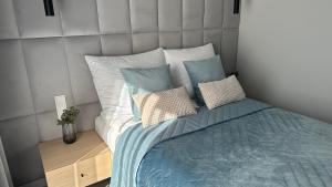 Un dormitorio con una cama con sábanas y almohadas azules. en Apartament Scandi, basen & spa, en Rewal 17 fotos más