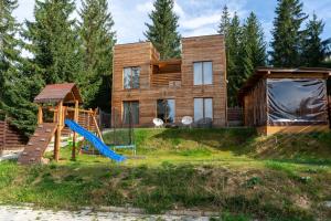 a wooden house with a slide and a playground at 2TowersCabin in Mărişel