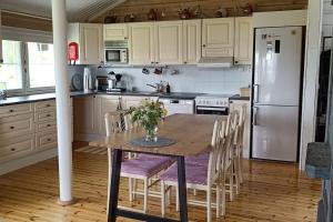 Una cocina con una mesa con sillas y un refrigerador. en Hirsimökki harjulla, en Pudasjärvi 9 fotos más