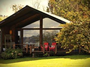 a cabin with red chairs in front of it at Casa Bauda de Chiloé in Castro