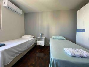 a room with two beds and a table with a lamp at 3 Quartos Amplo Ar Condicionado SQ54 in Maringá