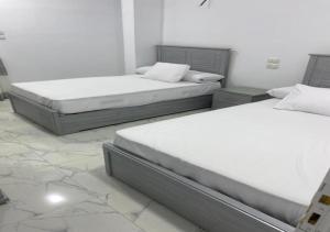 two twin beds in a room with marble floors at Alara Hostel ' Only girls ' in Naj‘ al Maḩaţţah +23 photos