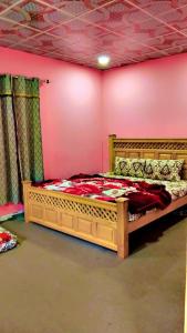 a bedroom with a wooden bed in a pink wall at Neelum View guest House in Dargai
