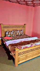 a wooden bed in a room with a pink wall at Neelum View guest House in Dargai