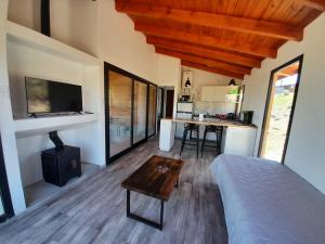 a bedroom with a bed and a table and a kitchen at Cabañas Altos de Kamiâre in Villa Yacanto