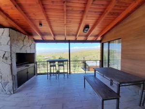 a porch with a bench and a table and a fireplace at Cabañas Altos de Kamiâre in Villa Yacanto