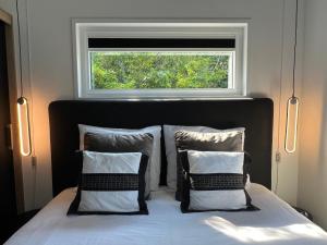 a bed with two pillows and a window above it at Qué Vida, Boutique Chalet aan Zee en Meer in Scharendijke