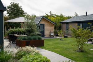 a garden with a table and chairs and a house at Qué Vida, Boutique Chalet aan Zee en Meer in Scharendijke