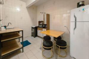 a kitchen with a table and a refrigerator at Apartamento Centro até 6 - EV01 in Maringá