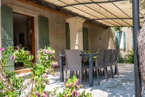 a table and chairs on a patio with flowers at Villa Lou Pitchoun entre Les Alpilles et Avignon in Graveson