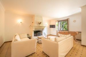 a living room with two white chairs and a fireplace at Villa Lou Pitchoun entre Les Alpilles et Avignon in Graveson