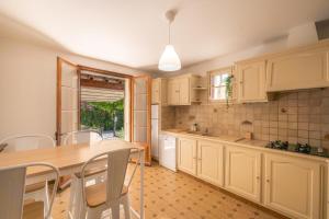 a kitchen with white cabinets and a table and chairs at Villa Lou Pitchoun entre Les Alpilles et Avignon in Graveson +27 photos