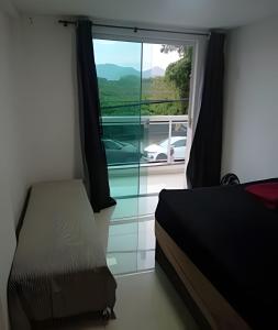 a bedroom with a bed and a window with a view at otimo apart 2 quartos no recreio dos bandeirantes in Rio de Janeiro